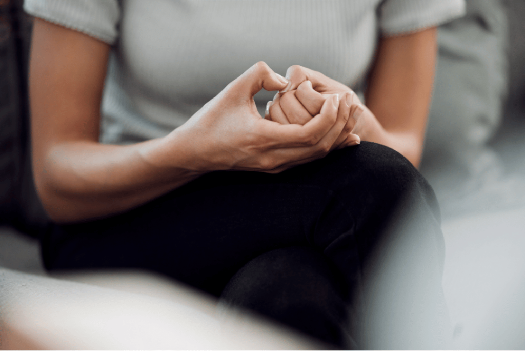 Close-up of a person clasping their hands, depicting anxiety and tension. The image captures the subtle yet powerful physical manifestation of anxiety, highlighting the importance of addressing mental health challenges in a supportive environment.