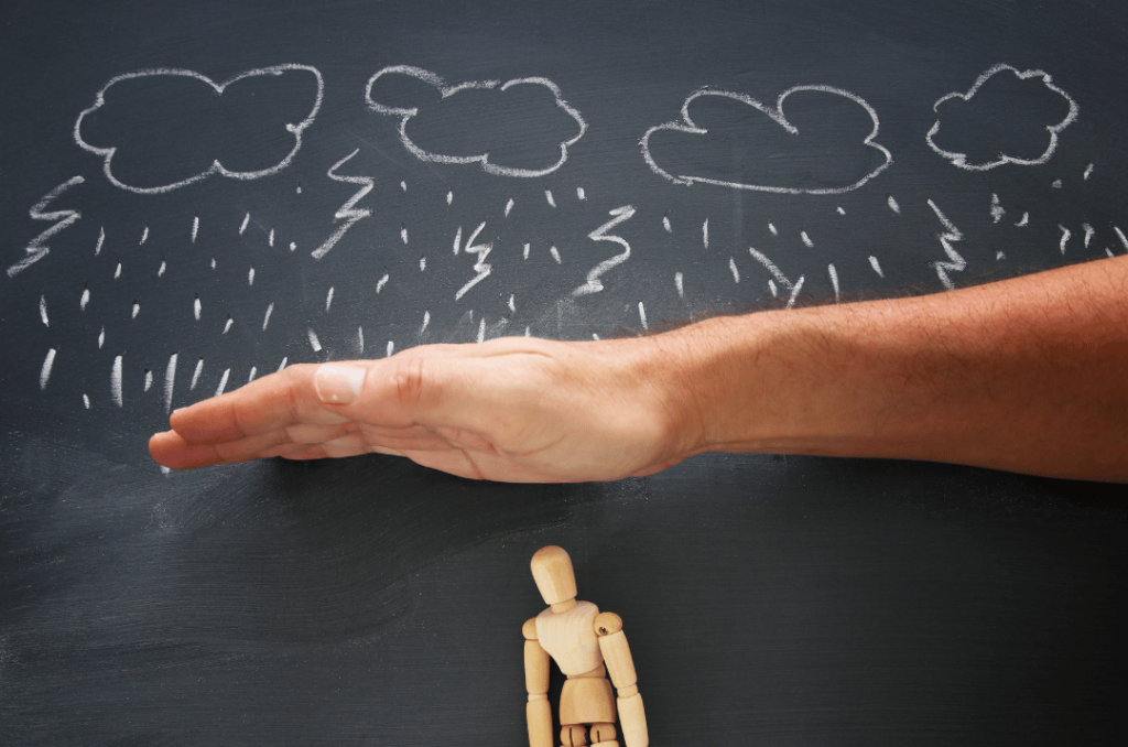 A symbolic image showing a hand shielding a small wooden figure from drawn rain clouds, representing protection and support during difficult times.