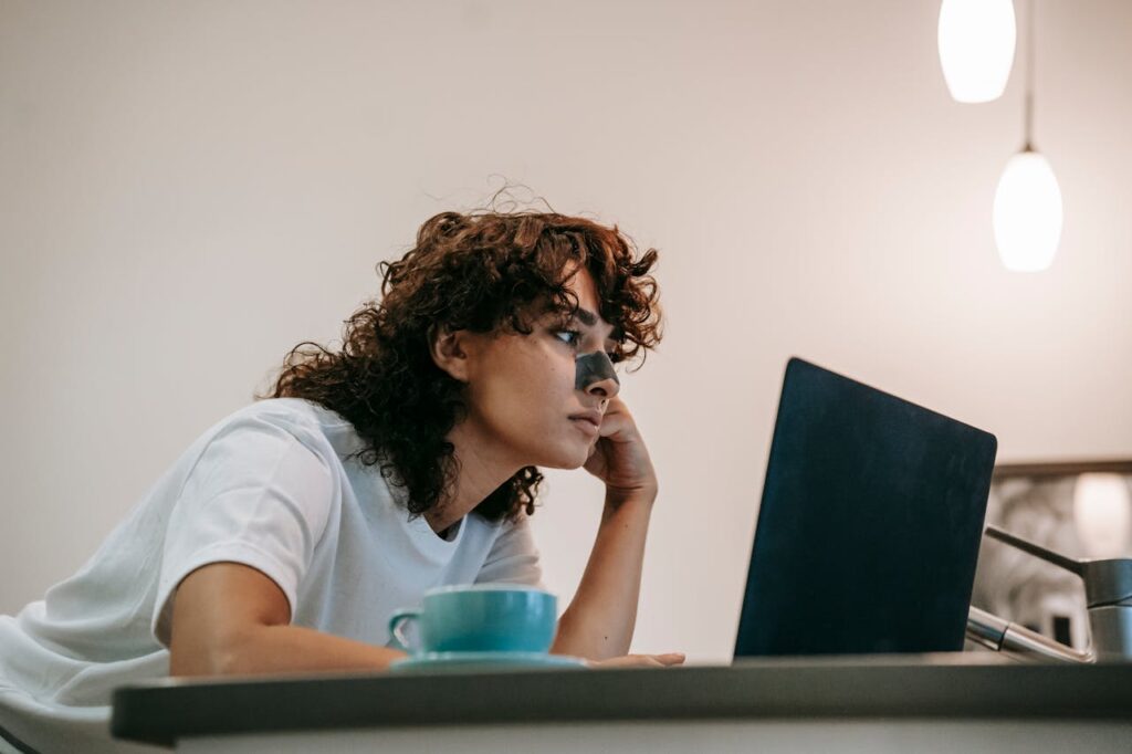 A girl using a laptop, appearing slightly sad and frustrated with her daily life, possibly searching for something on her laptop.