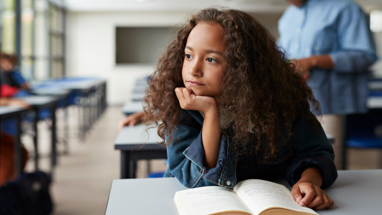 Image of a young girl with curly hair, deep in thought and showing signs of tension, representing someone with ADHD deep in contemplation.