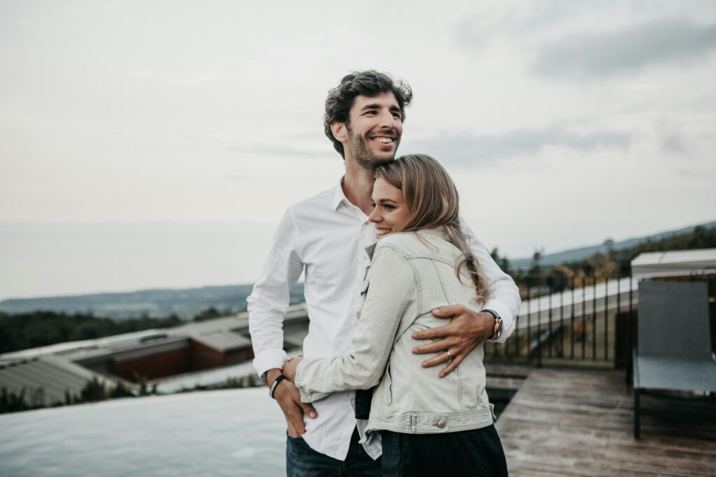 Image of a couple embracing each other outdoors on a beautiful day and both are looking happy