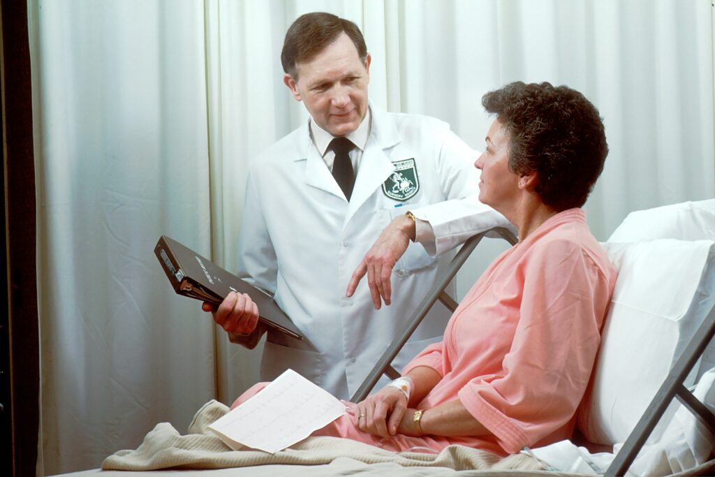A male doctor conducts a medical examination of a female patient while engaged in discussion, fostering open communication and patient-centered care in a hospital setting.