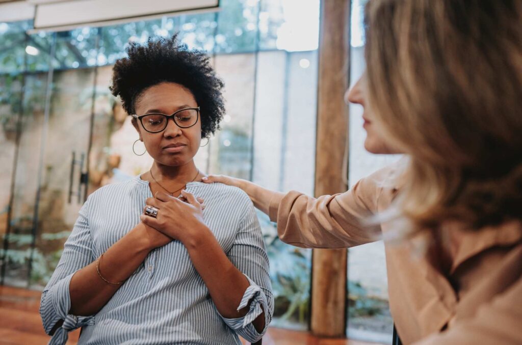 A woman displays emotional intelligence by displaying vulnerable body language in front of another woman.