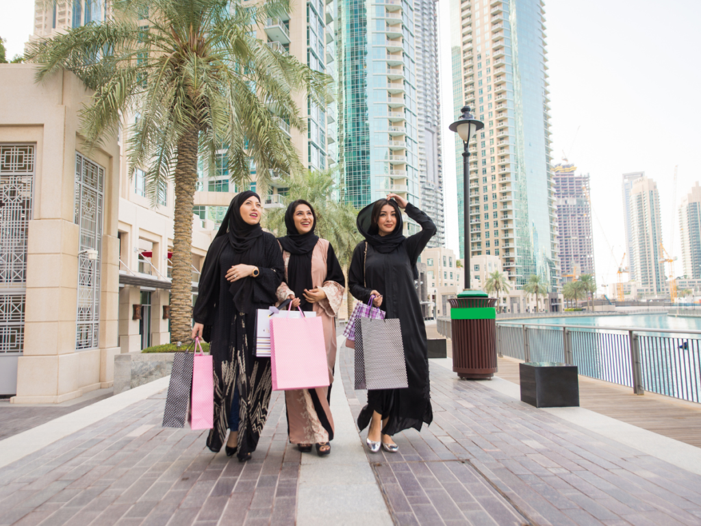 Three women are strolling on a Dubai street (Dubai Marina) while carrying shopping bags. 