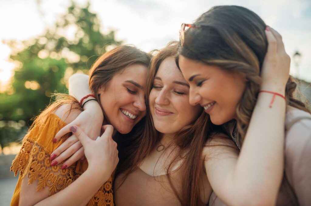 Three smiling women hug each other