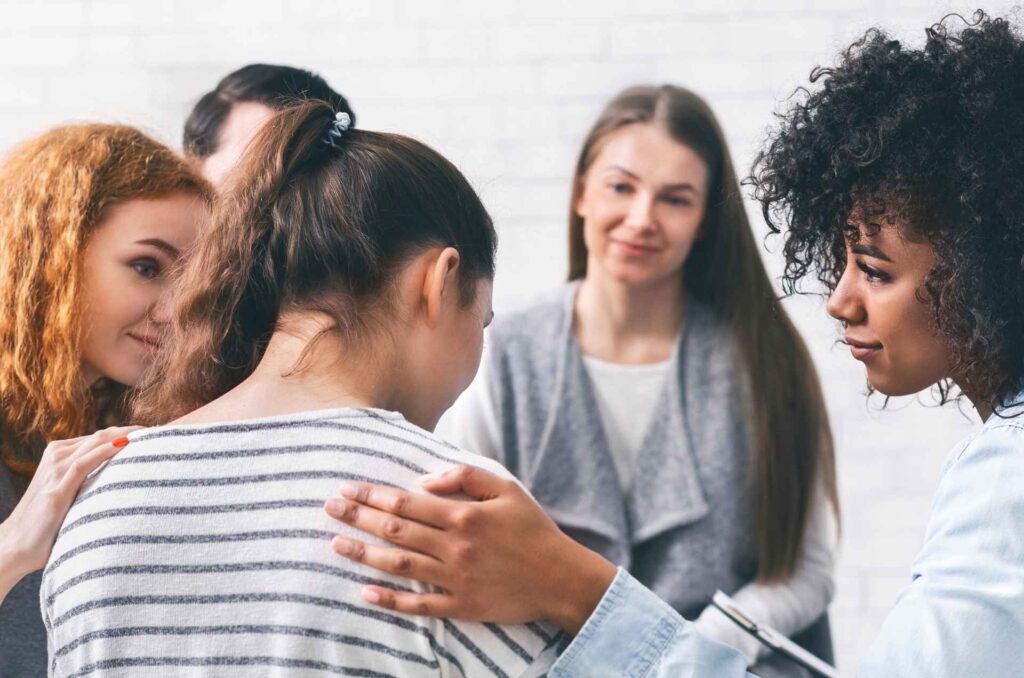 A woman receives pats on the back and smiles from other women. 