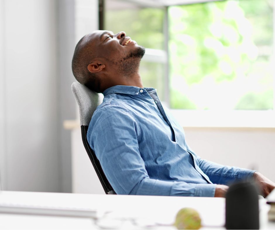 A man leans back on his chair looking relaxed after his deep breathing exercises