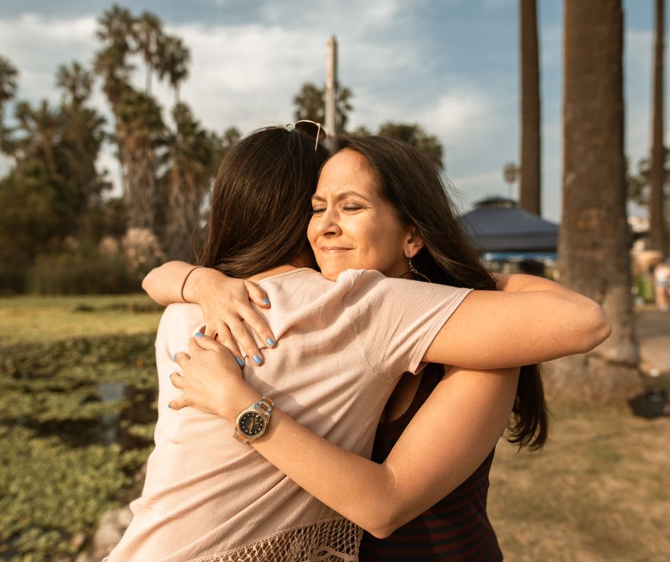 A woman comforts another woman by giving her a hug