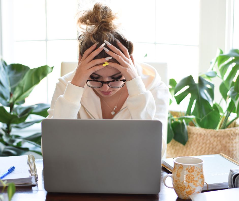 A woman who suffers from workplace burnout holds her head in her hands. 