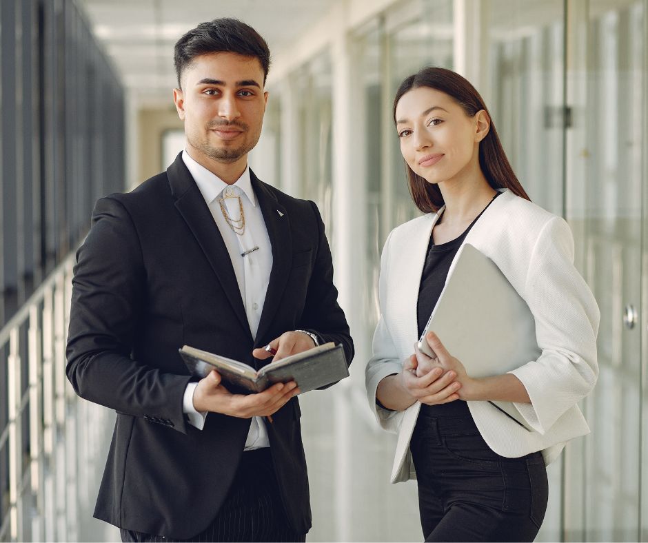 A man and a woman are smiling for the camera while in the workplace.