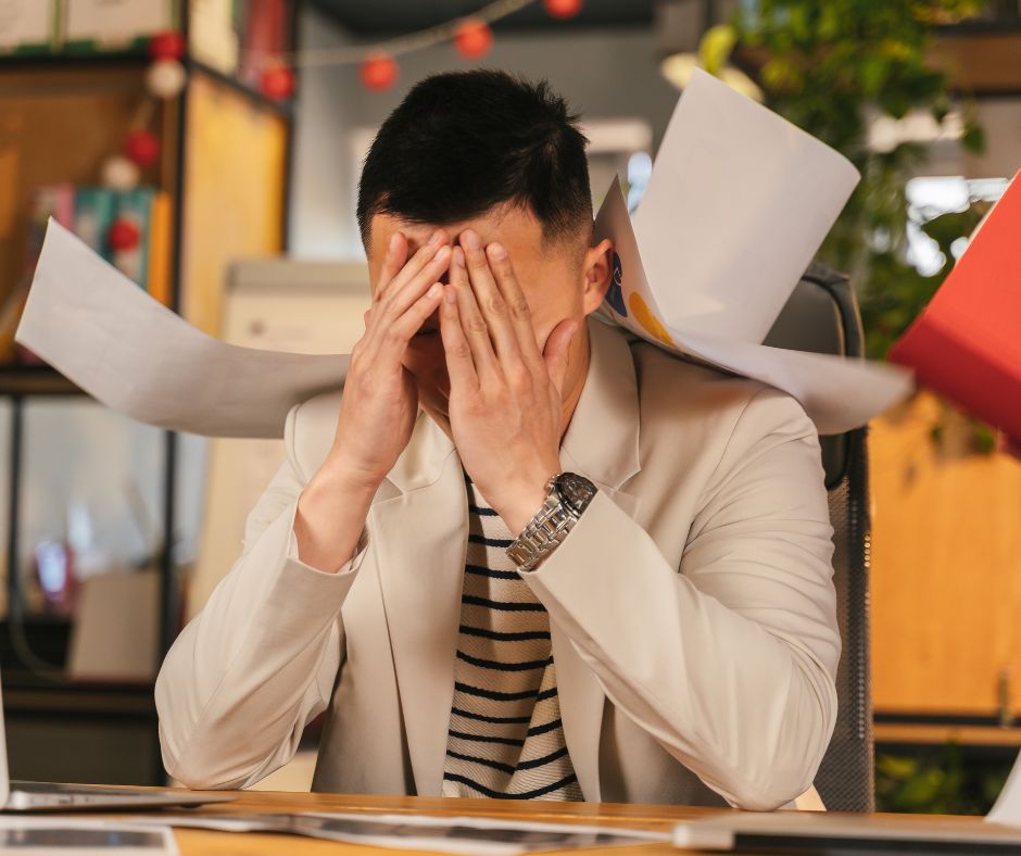 A stressed out man experiencing culture shock at the office covers his face.