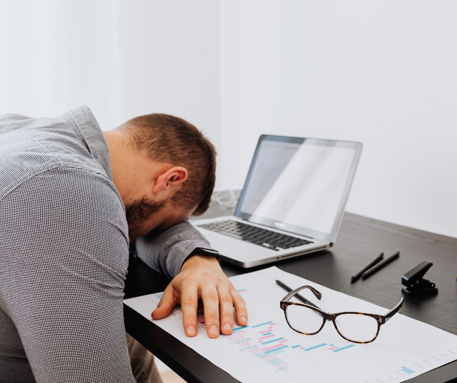 A person suffering from burnout rests his head on his desk