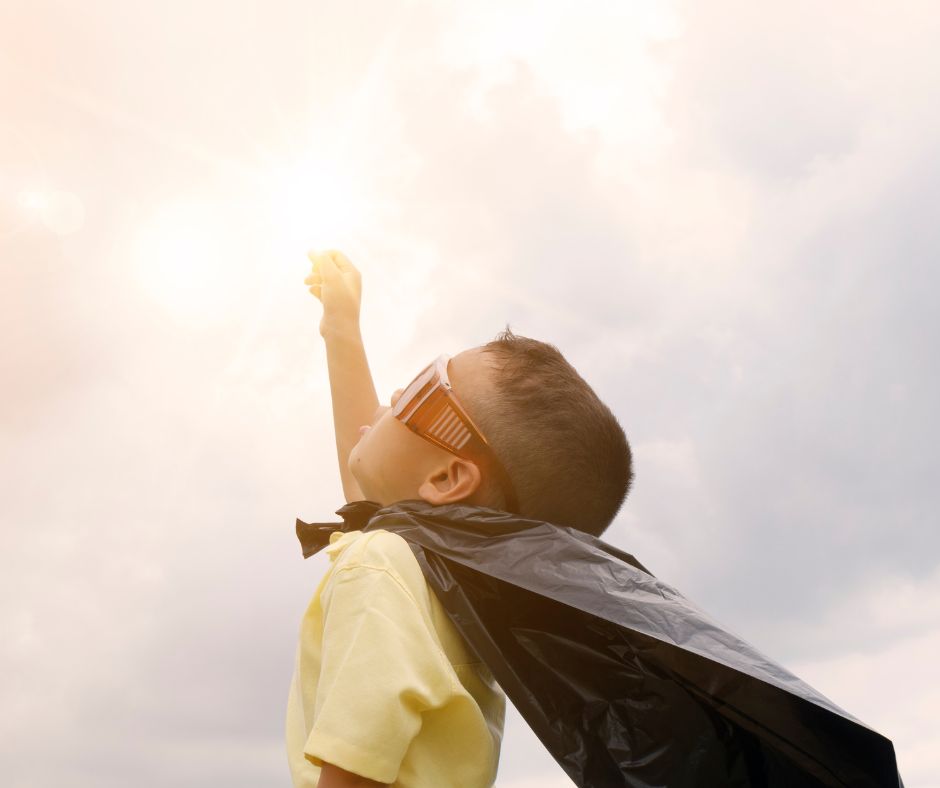 A child in a costume cape strikes a superhero pose
